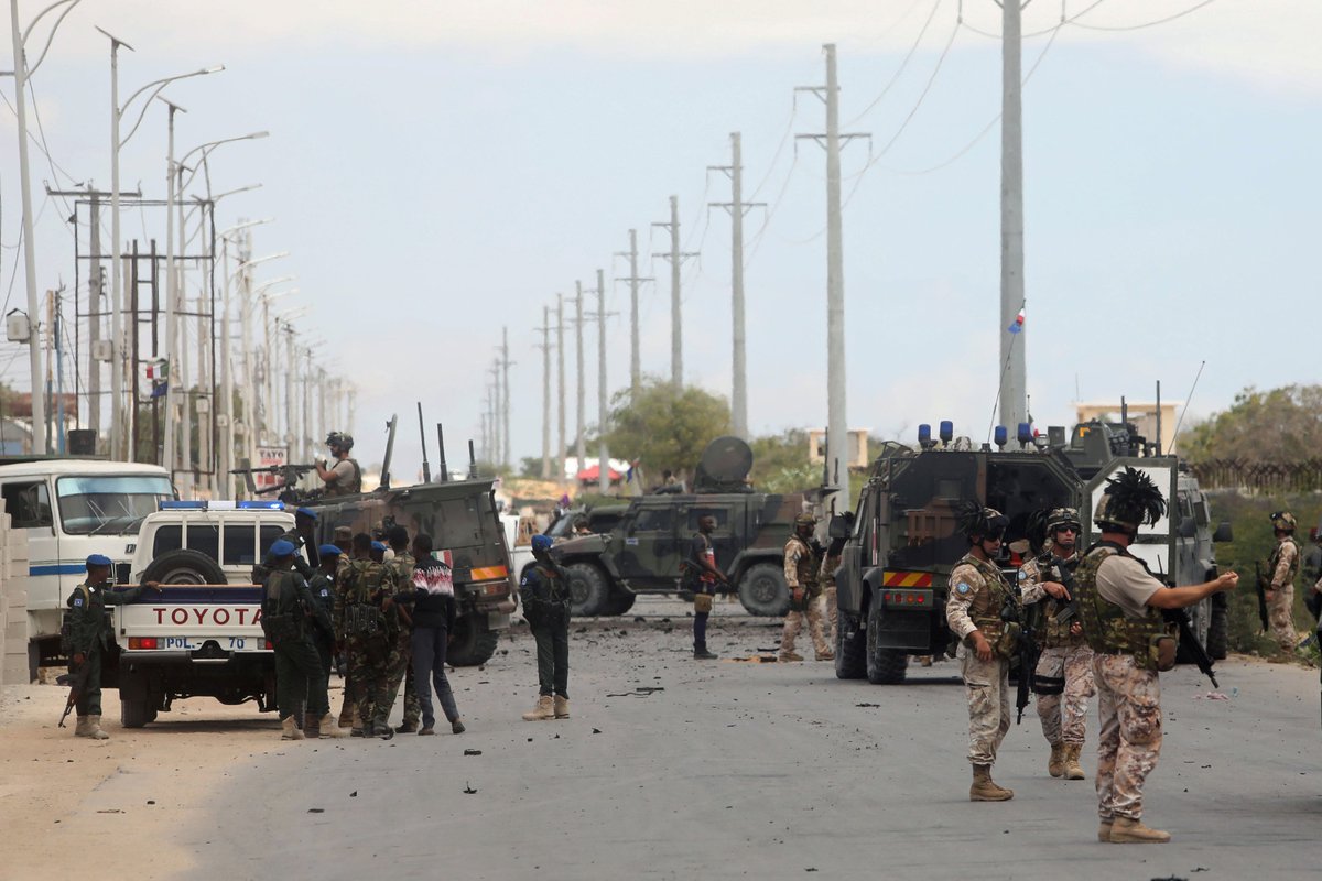 are seen near armoured vehicles at the scene of an attack on an